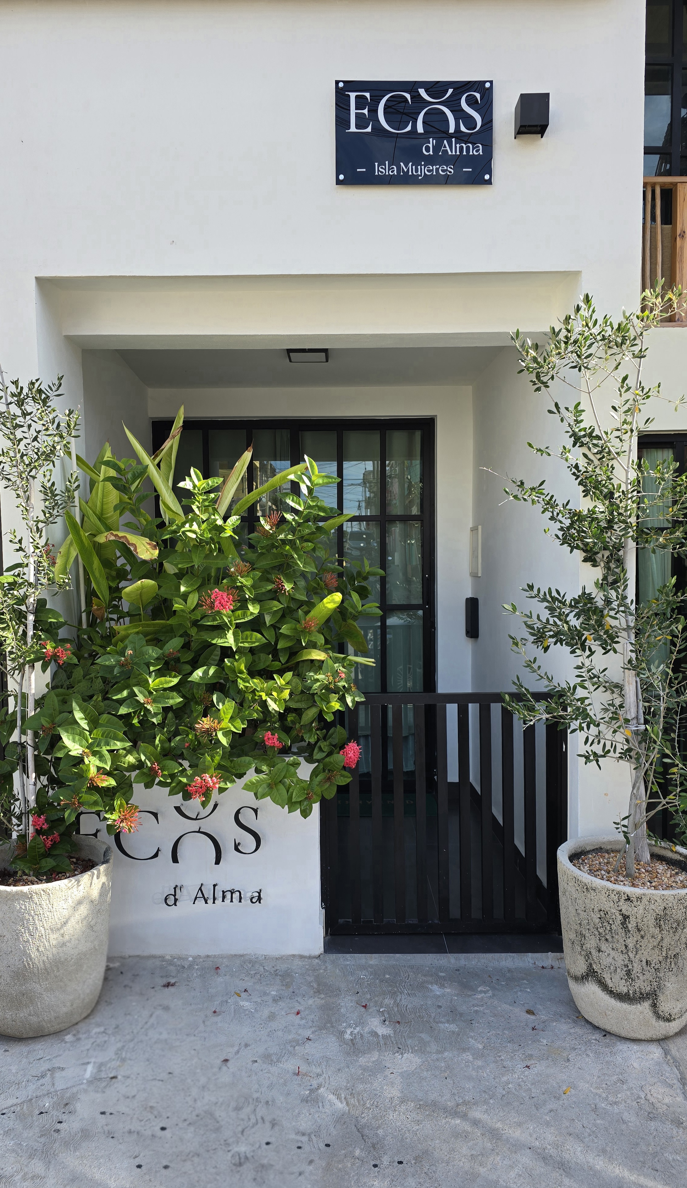Casa Ecos d'Alma entrance sign, framed by tropical flowers